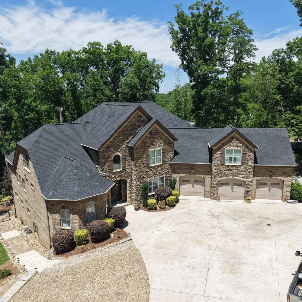 A large brick home with a dark shingle roof viewed from above.